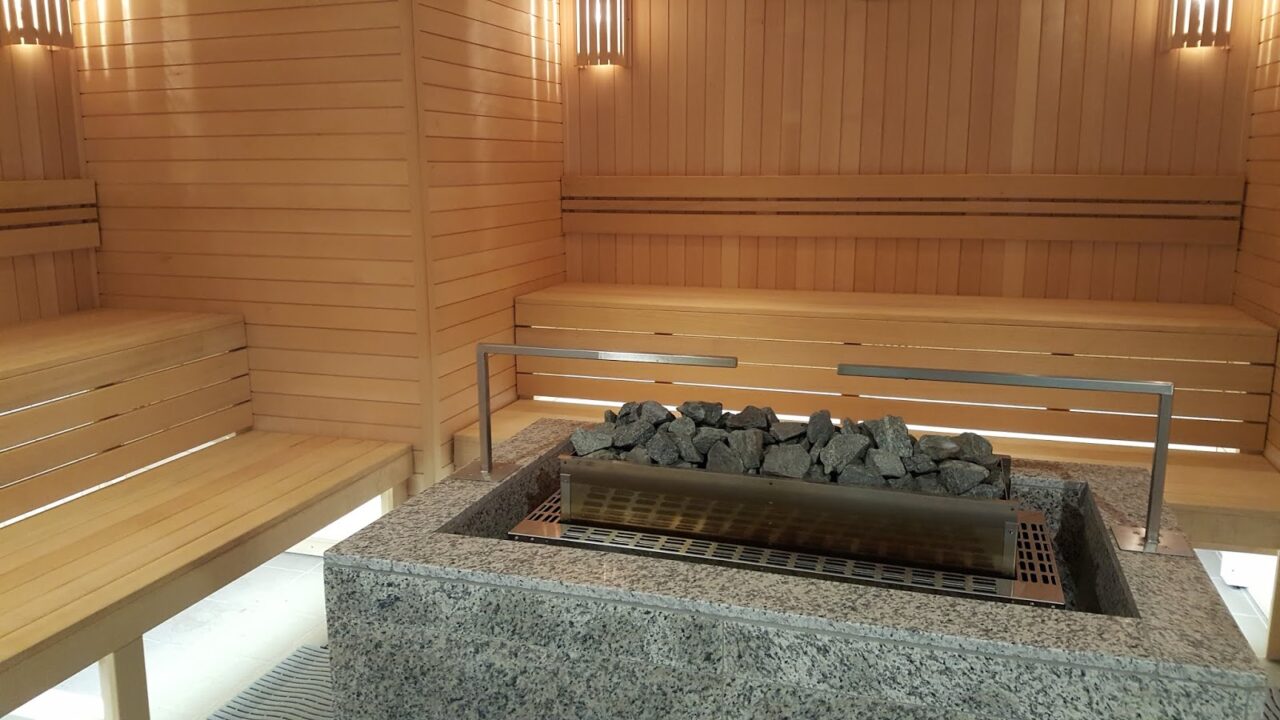 A pristine modern wooden sauna cabin with a central stone heater