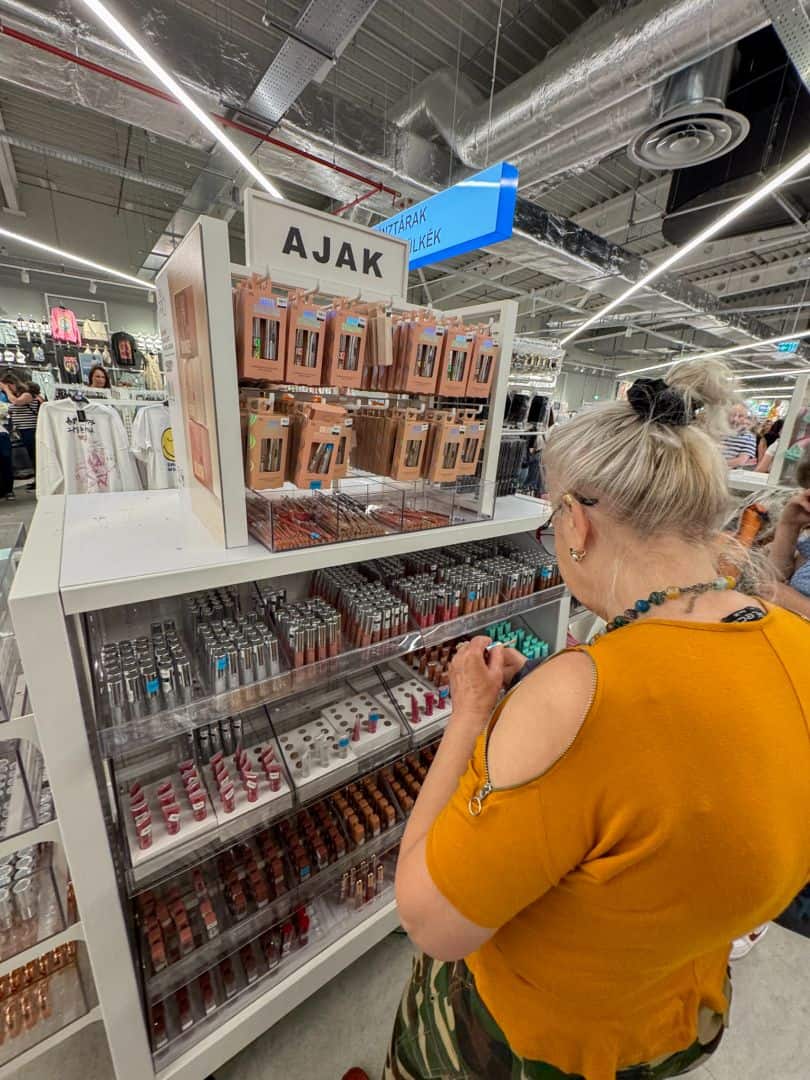 A woman shopping for affordable cosmetics in the densely stocked makeup section