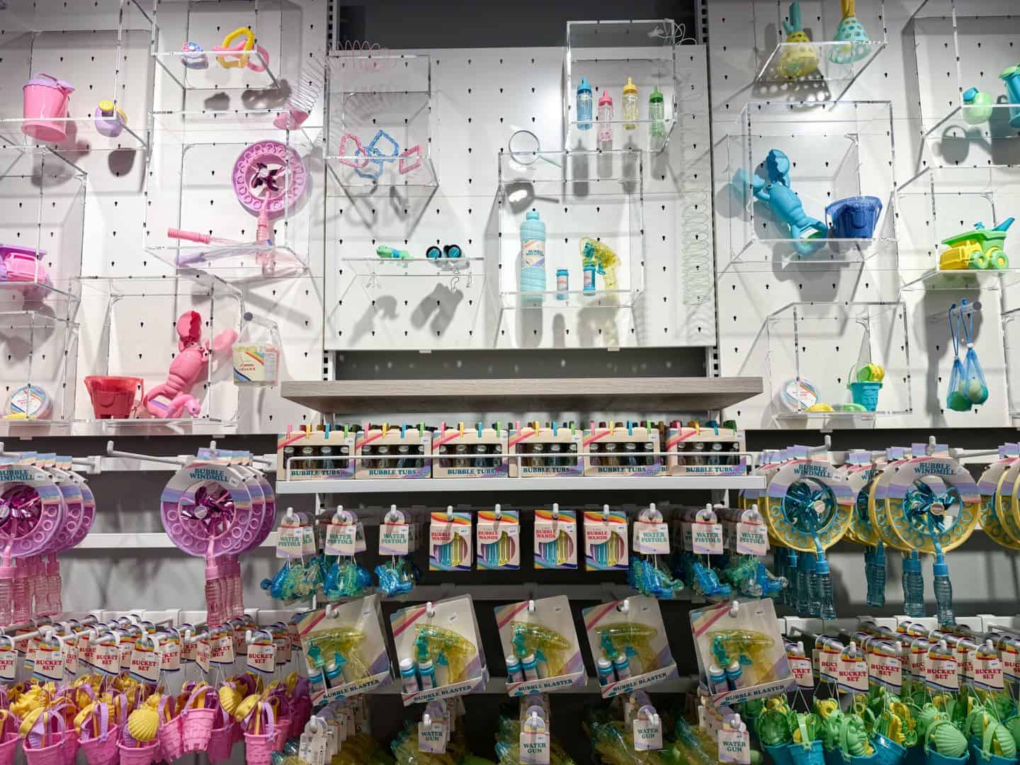 A wall display of children's outdoor summer toys like water guns and bubble wands