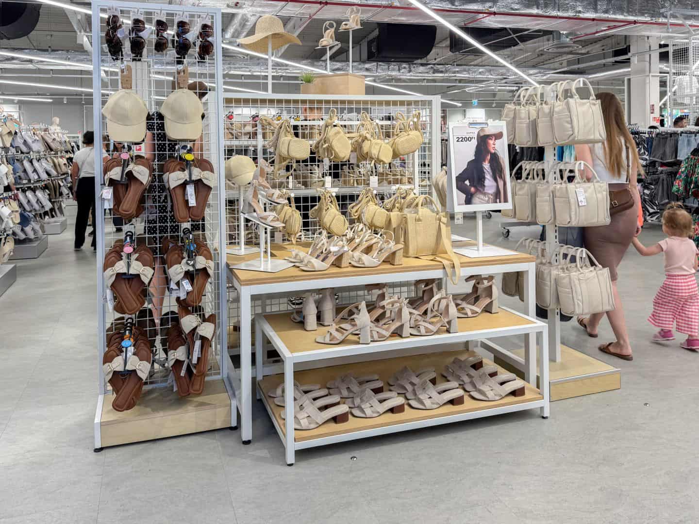 A retail display of women's summer accessories, including strappy heels and straw bags