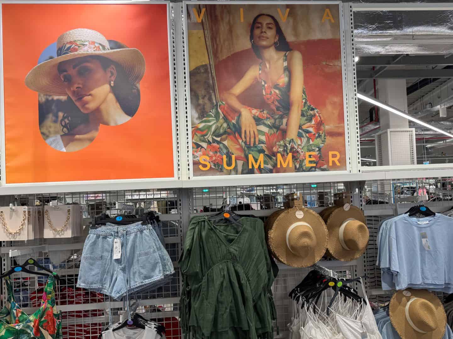 Trendy summer clothing including denim shorts and green blouses on retail display