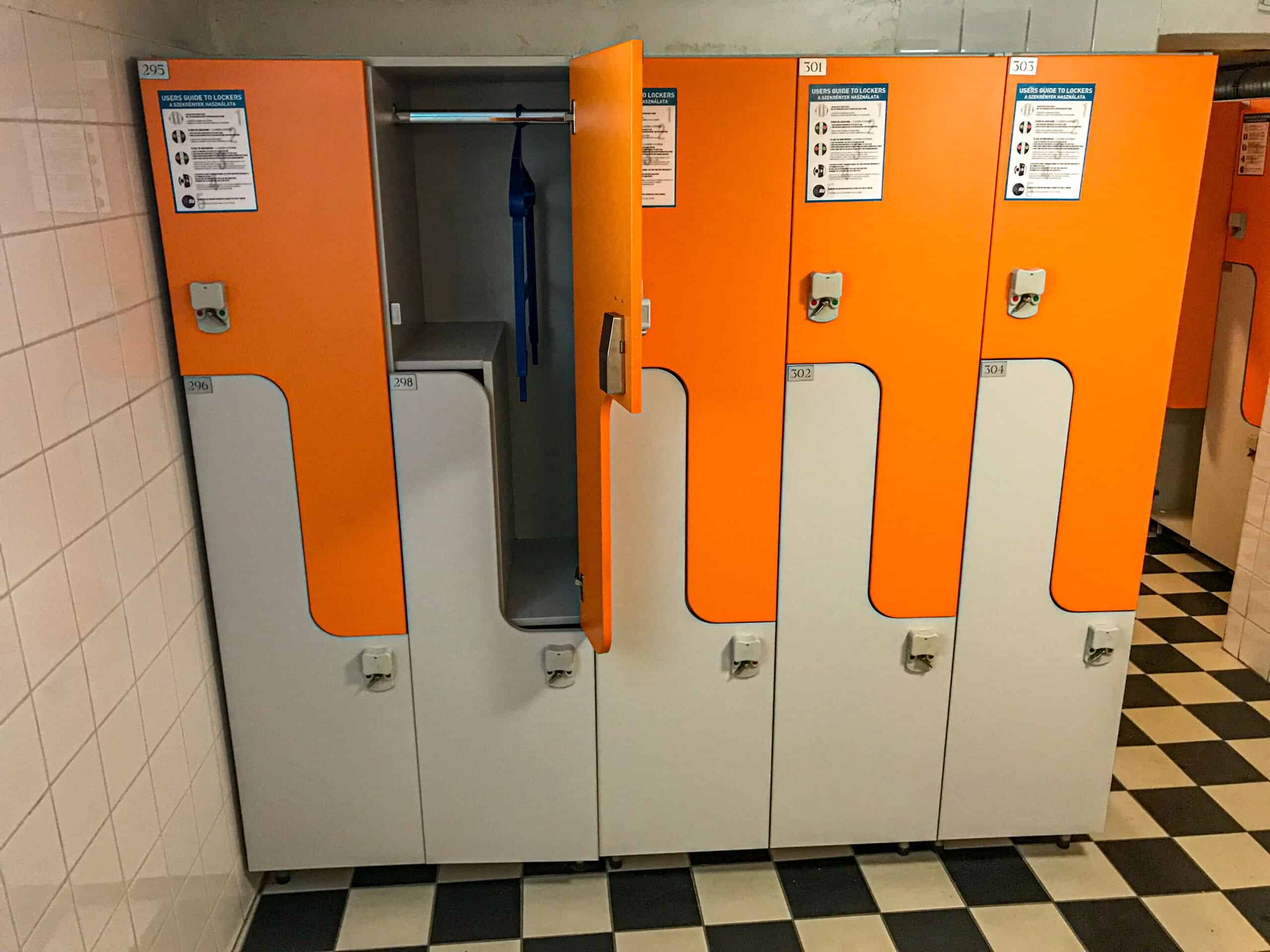 The clean, functional locker hall filled with white electronic lockers at Lukács Baths