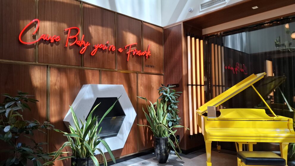 A bright yellow grand piano and neon sign in the Pullman Budapest lobby
