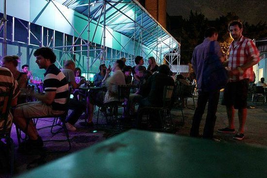 People drinking under a lit scaffolding structure at Racskert