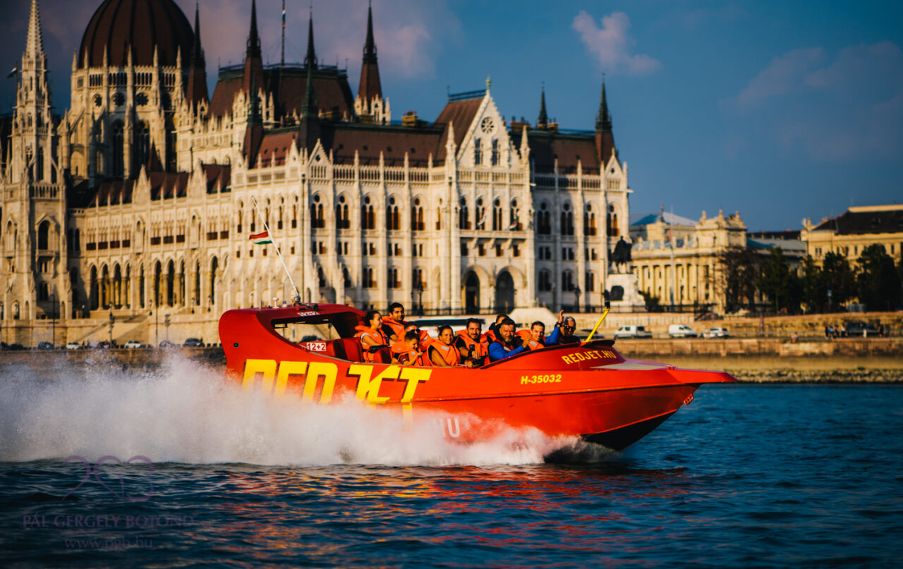 The red RedJet boat speeding fast and kicking up water spray