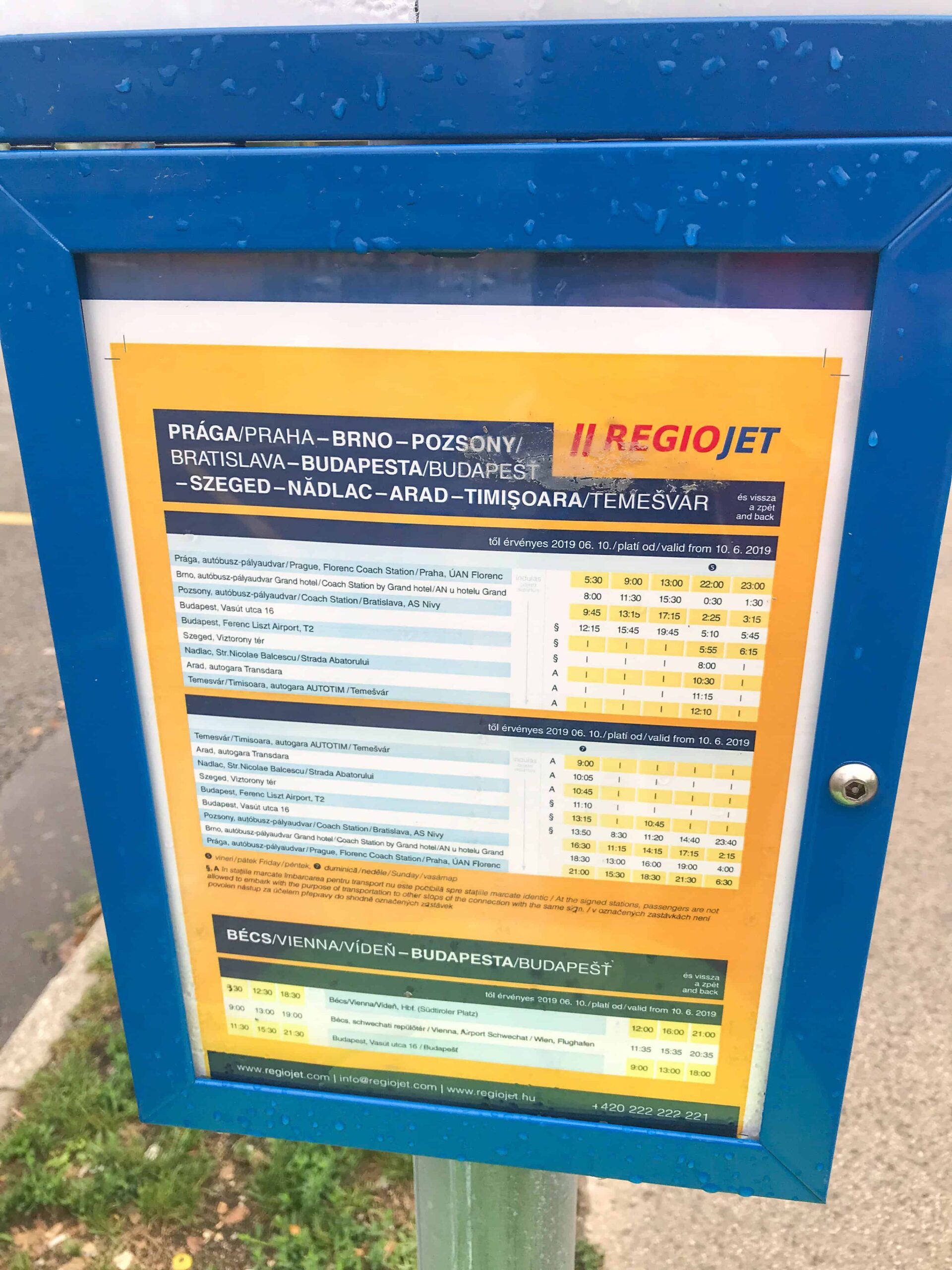 A yellow printed RegioJet departure schedule at the Kelenföld bus platform