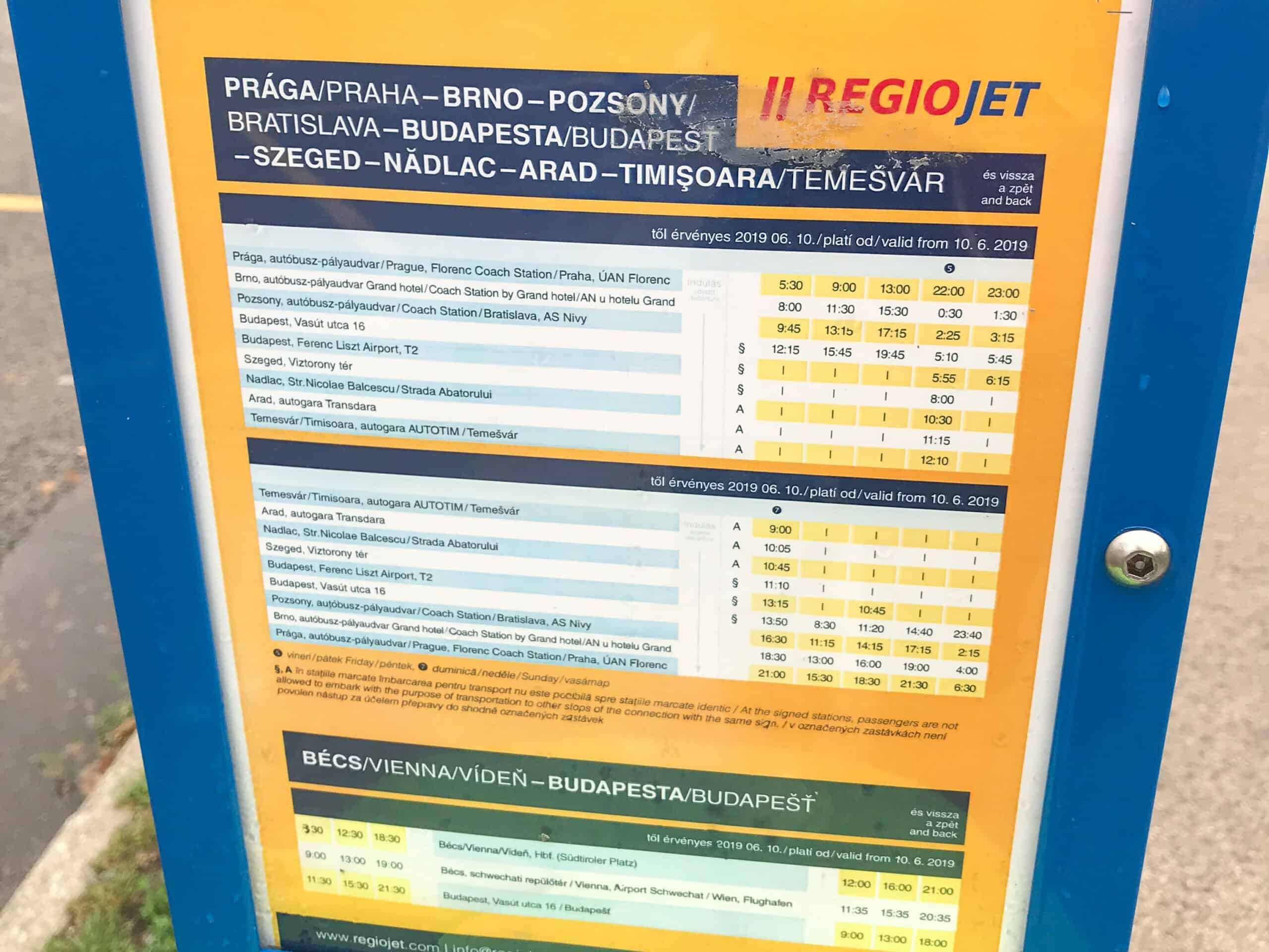 A yellow printed RegioJet departure schedule posted at the Kelenföld terminal