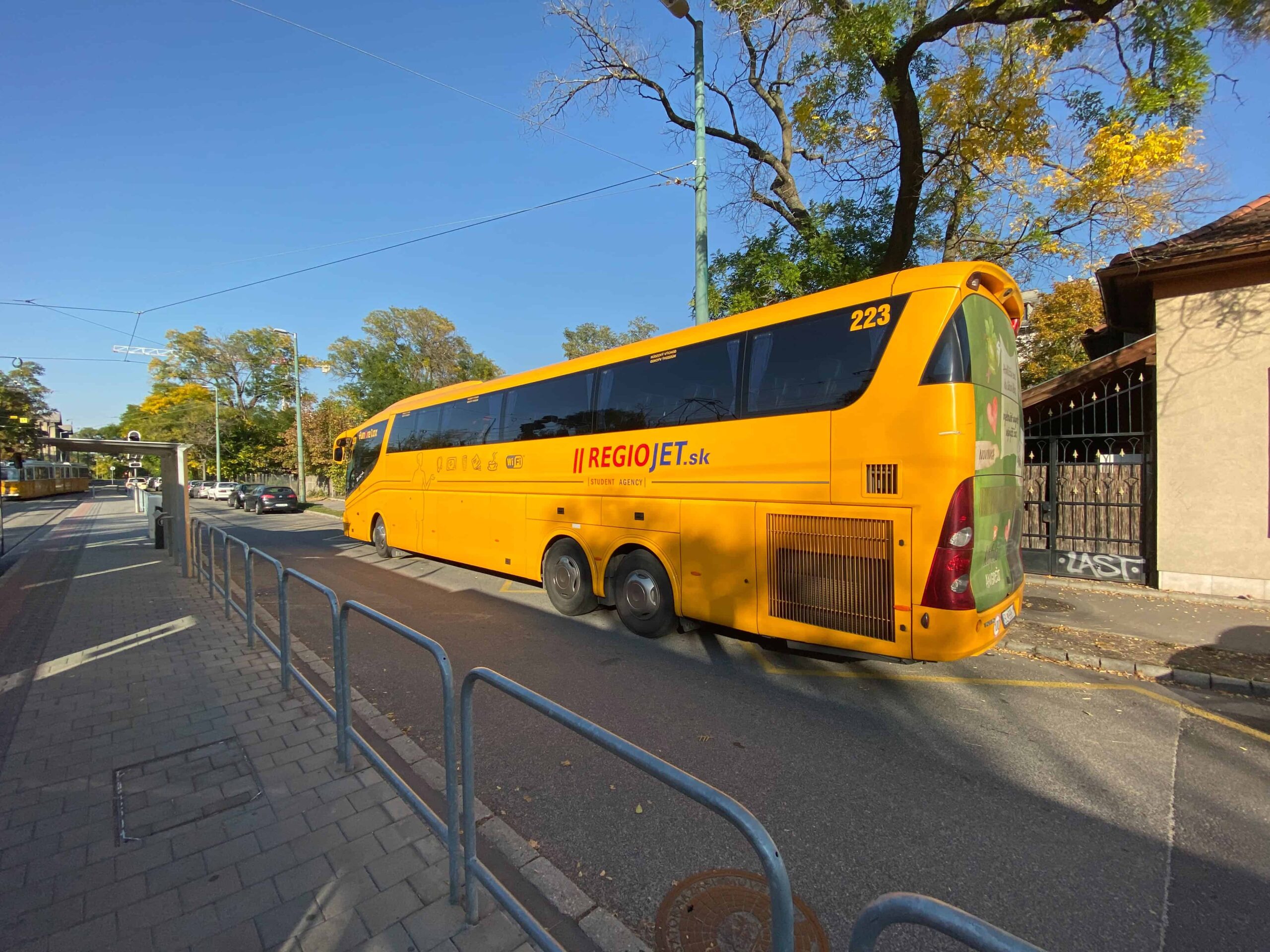 A bright yellow RegioJet coach bus arriving at the Budapest terminal