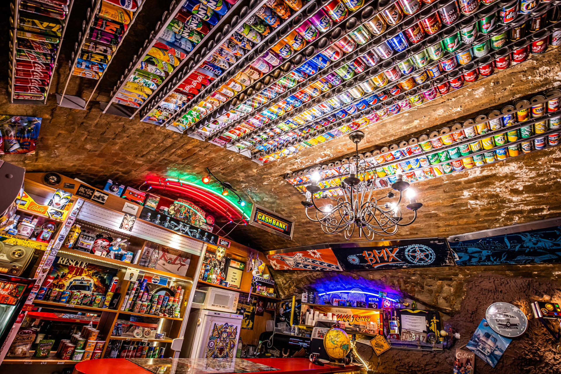 The eclectic bar area inside the museum featuring a ceiling covered in backed-lit crushed aluminum cans
