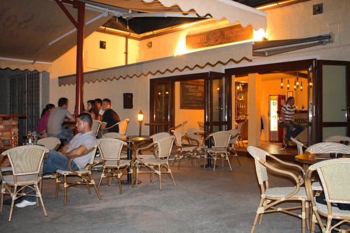 Guests sitting at bistro tables on the outdoor terrace of the Rezangyal Palinkahaz bar