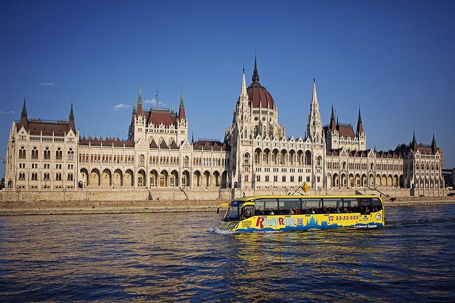 The RiverRide bus functioning as a boat cruising past the Hungarian Parliament