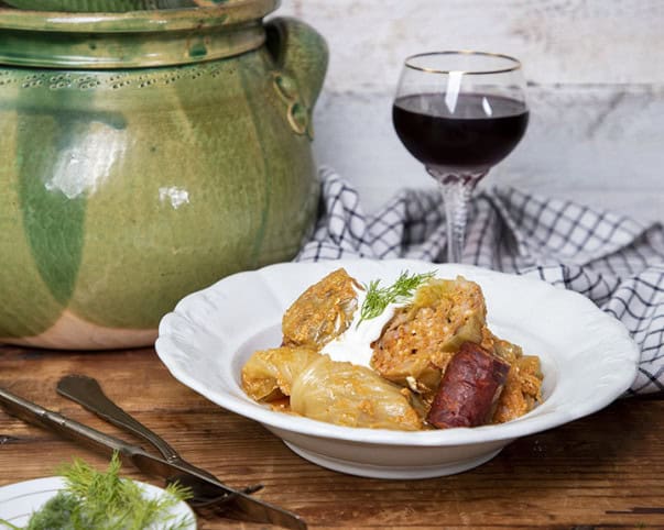 Stuffed cabbage served with sausage, sour cream, and a glass of red wine