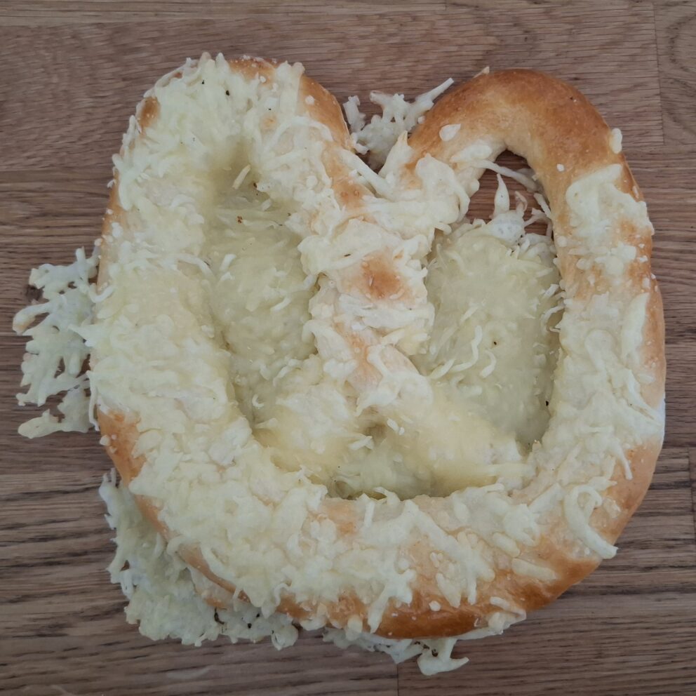 A large, soft baked pretzel thick with melted and crisped Trappista cheese