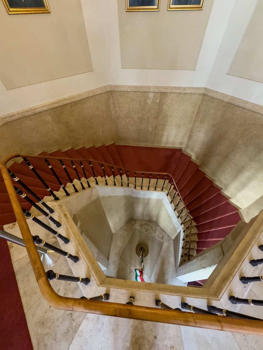 An ornate elliptical spiral staircase inside Sandor Palace