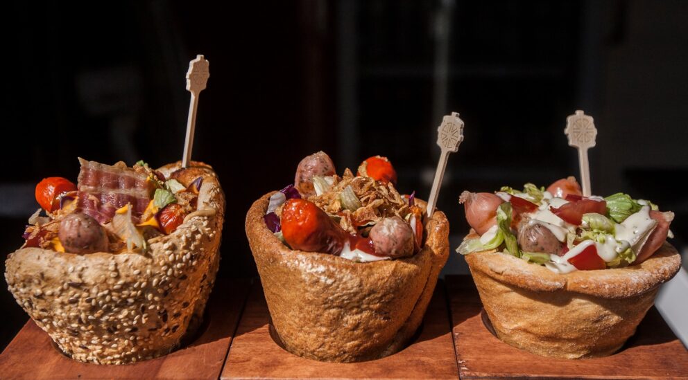 Three chimney cake cones filled with savory sausages and vegetables