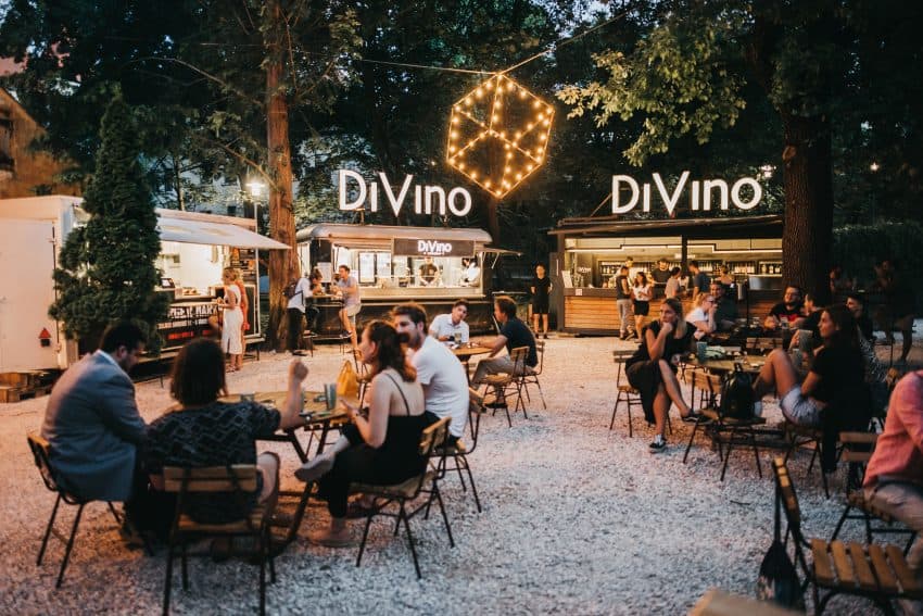 People socializing at a gravel garden with food trucks at dusk