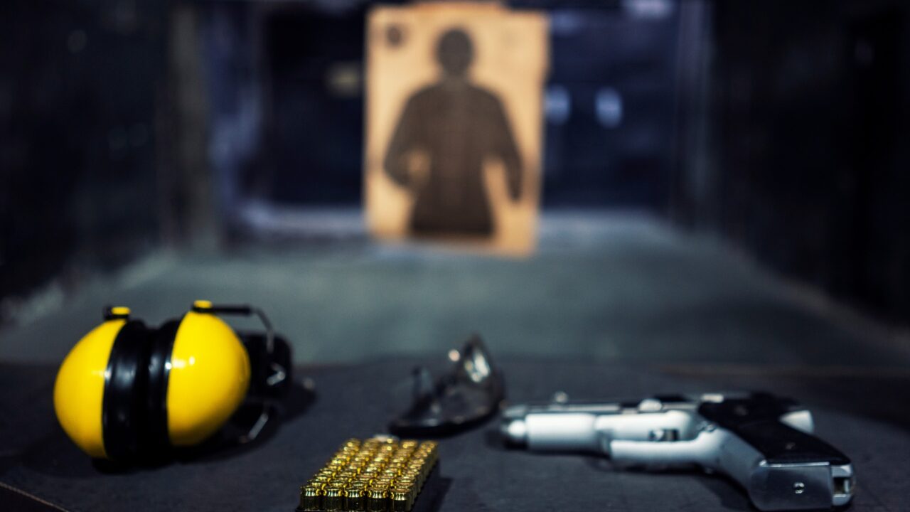 Safety ear muffs, glasses, a handgun, and ammunition ready on the firing line table