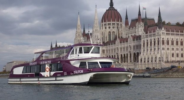 A purple and white Silverline catamaran sailing past the Hungarian Parliament building