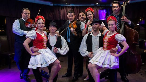 A traditional Hungarian folk dance troupe and live band posing inside the cruise boat