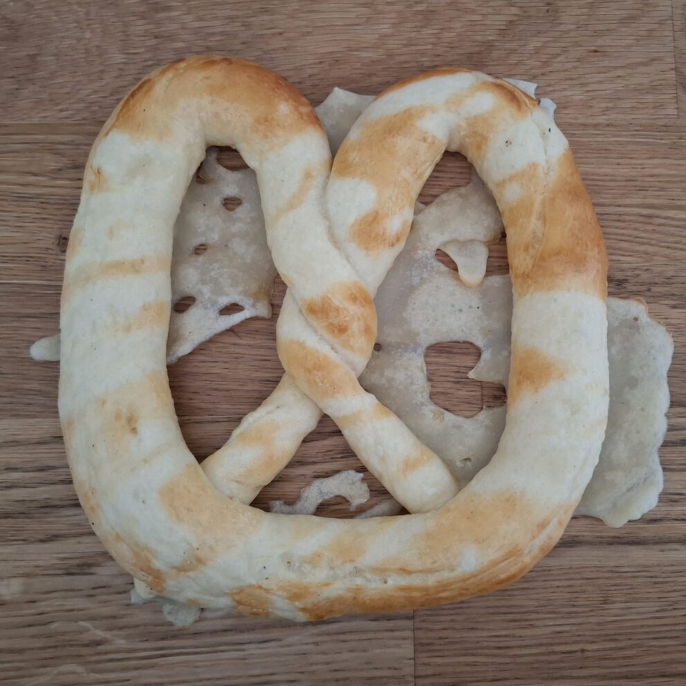 A large Hungarian soft pretzel heavily decorated with distinct streaks of baked white salt paste