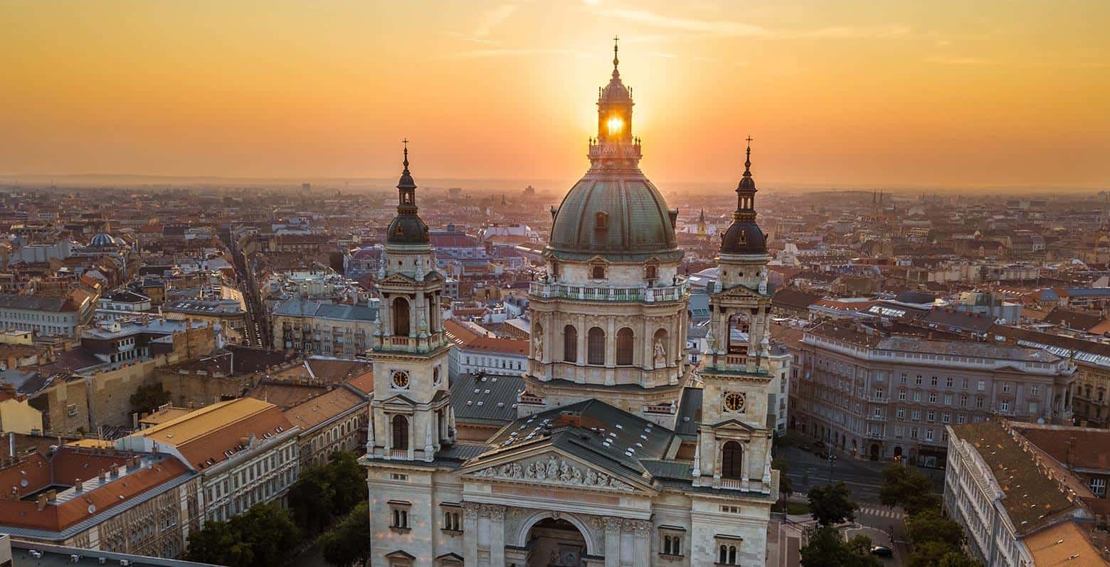 An aerial view of the basilica's green dome towering over the city at sunset