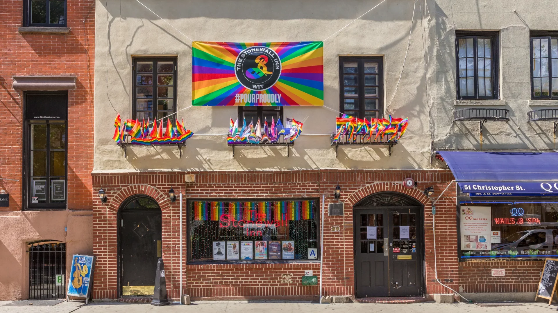 The historic red brick facade of the Stonewall Inn decorated with Pride banners
