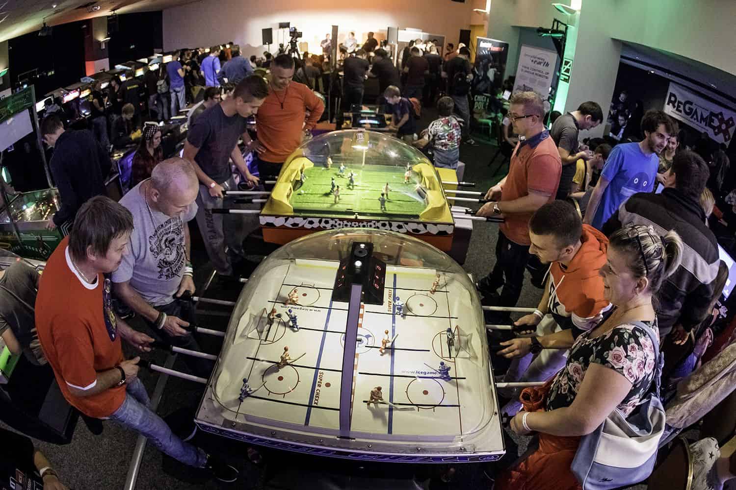 Groups of people playing a Super Chexx bubble hockey dome game and foosball