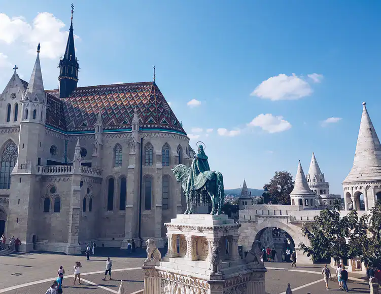 Guests swimming in the massive, bright blue outdoor pool at Széchenyi Thermal Bath
