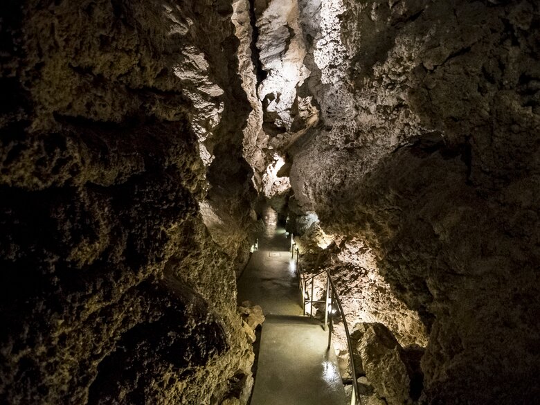 Tourists walking on a paved pathway inside the Szemlő-hegyi Cave in Budapest