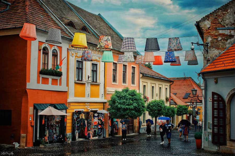 Colorful lampshades hanging over a cobblestone street in Szentendre