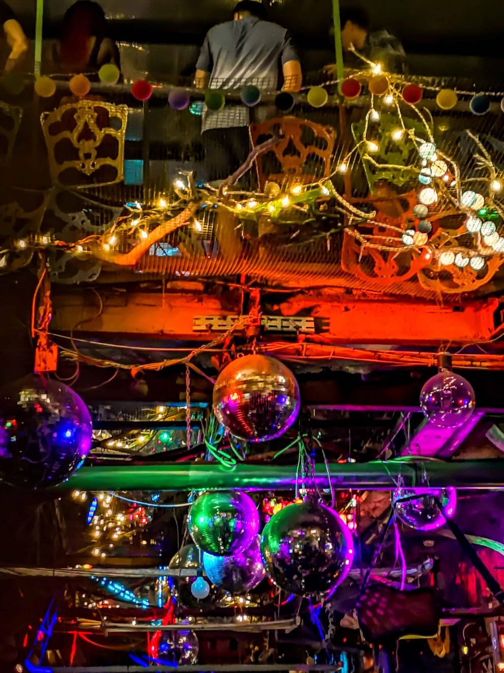 Looking up at disco balls and the wire mesh floor of the upper level in Szimpla