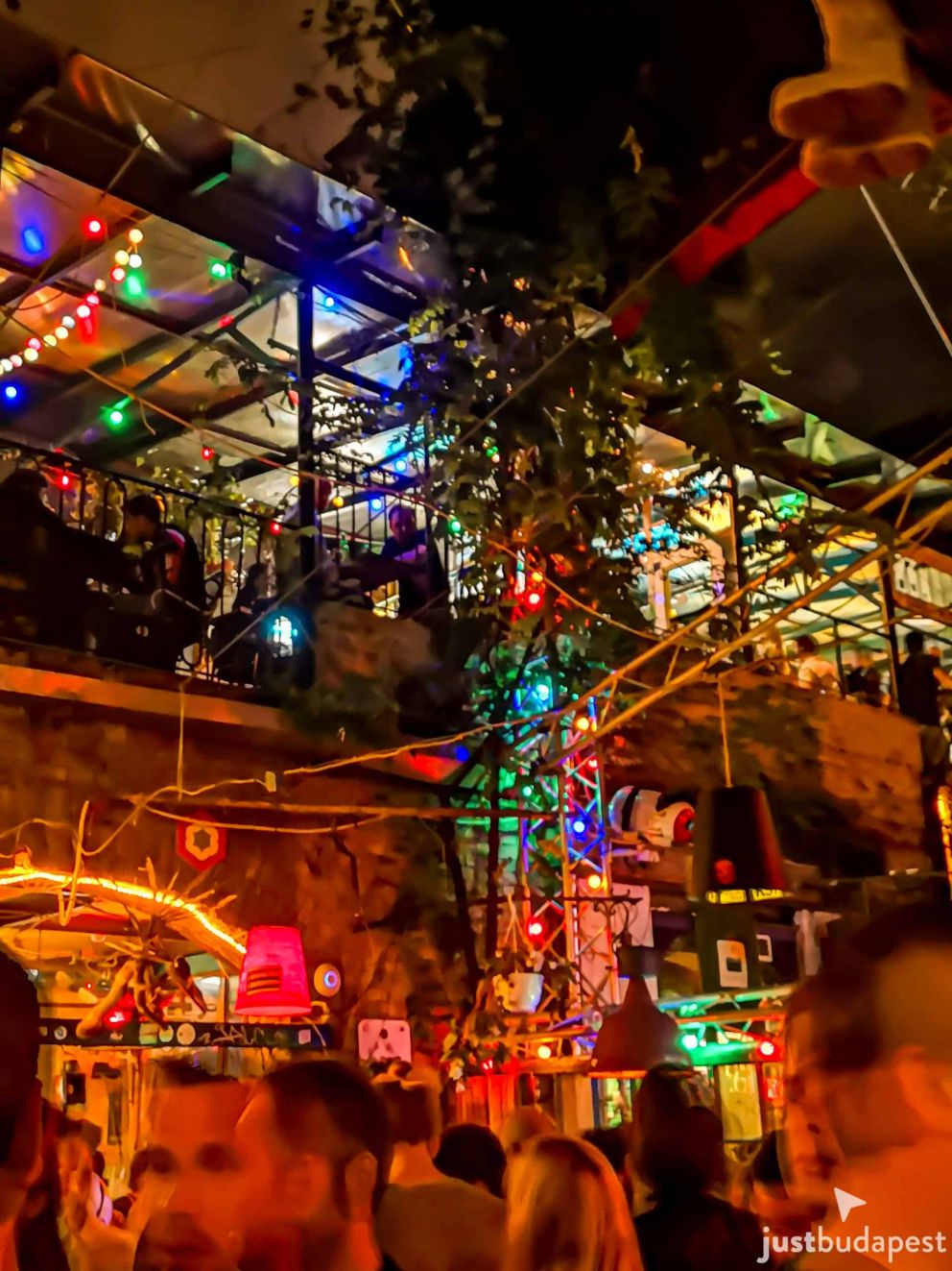 A massive crowd partying inside the creatively lit, multi-level Szimpla Kert