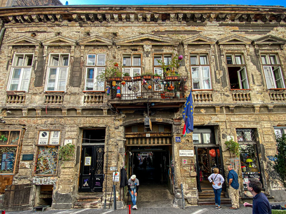 The dilapidated but charming exterior facade of the Szimpla Kert building during the day