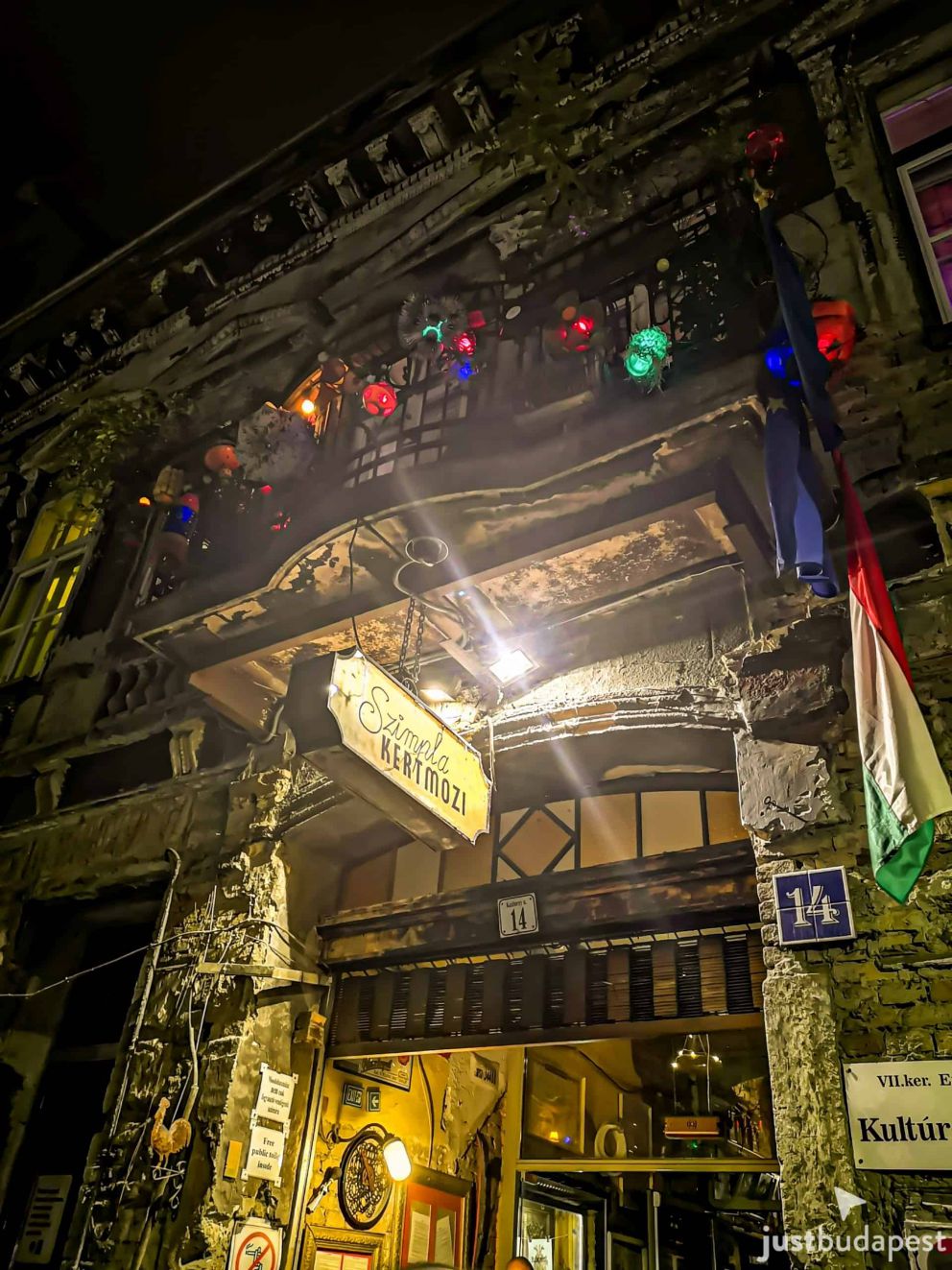 The illuminated Szimpla Kertmozi sign at the entrance of the ruin pub at night