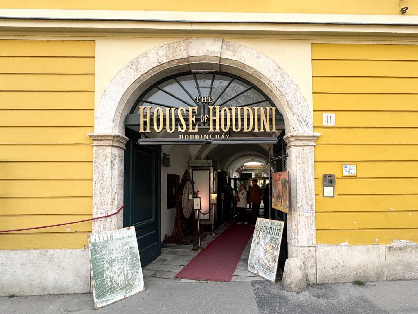 The grand arched entrance and sign of The House of Houdini in Budapest