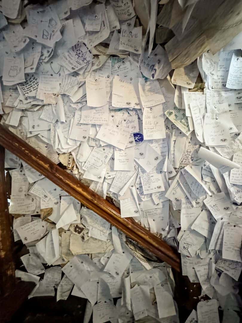 A chaotic, dense collage of thousands of paper notes and drawings covering the pub wall