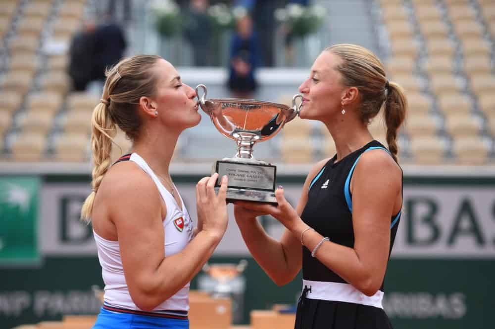 Timea Babos and her doubles partner kissing their Grand Slam tennis trophy