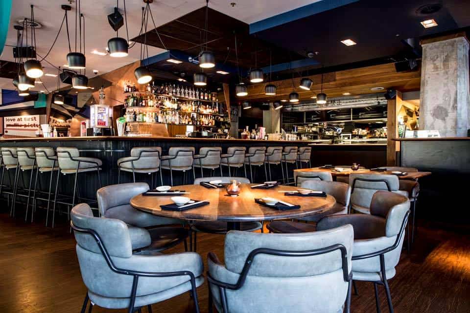 Round wooden tables and grey leather chairs in the TOKIO dining area