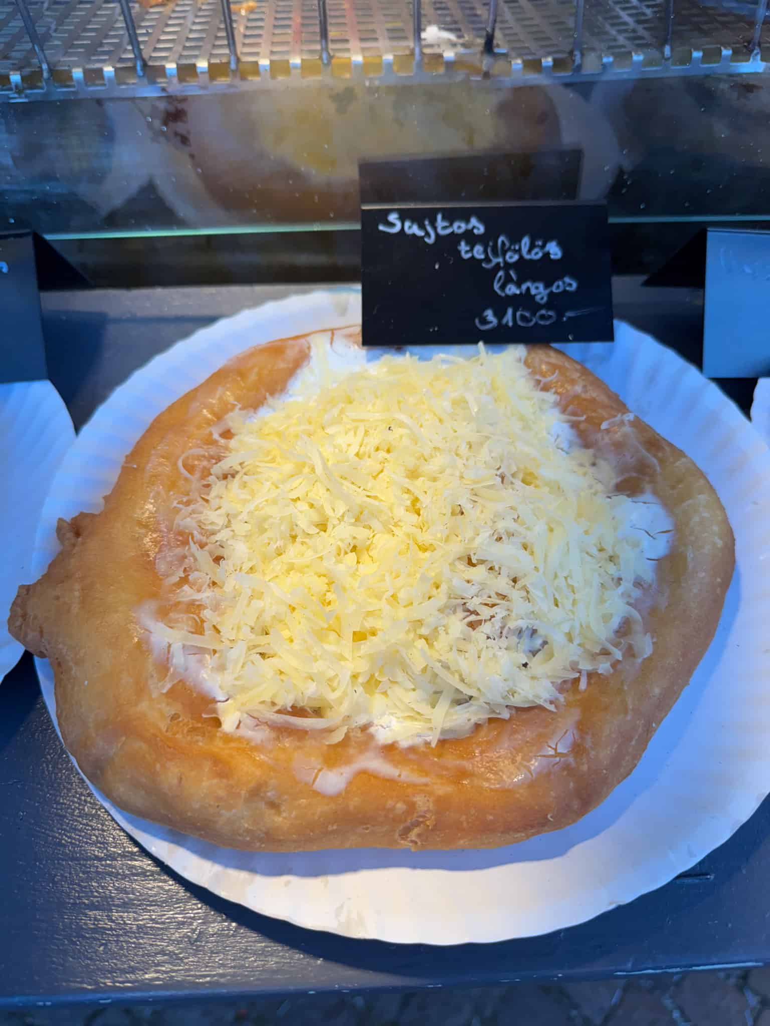 Three pieces of deep-fried Langos topped with sour cream and grated cheese