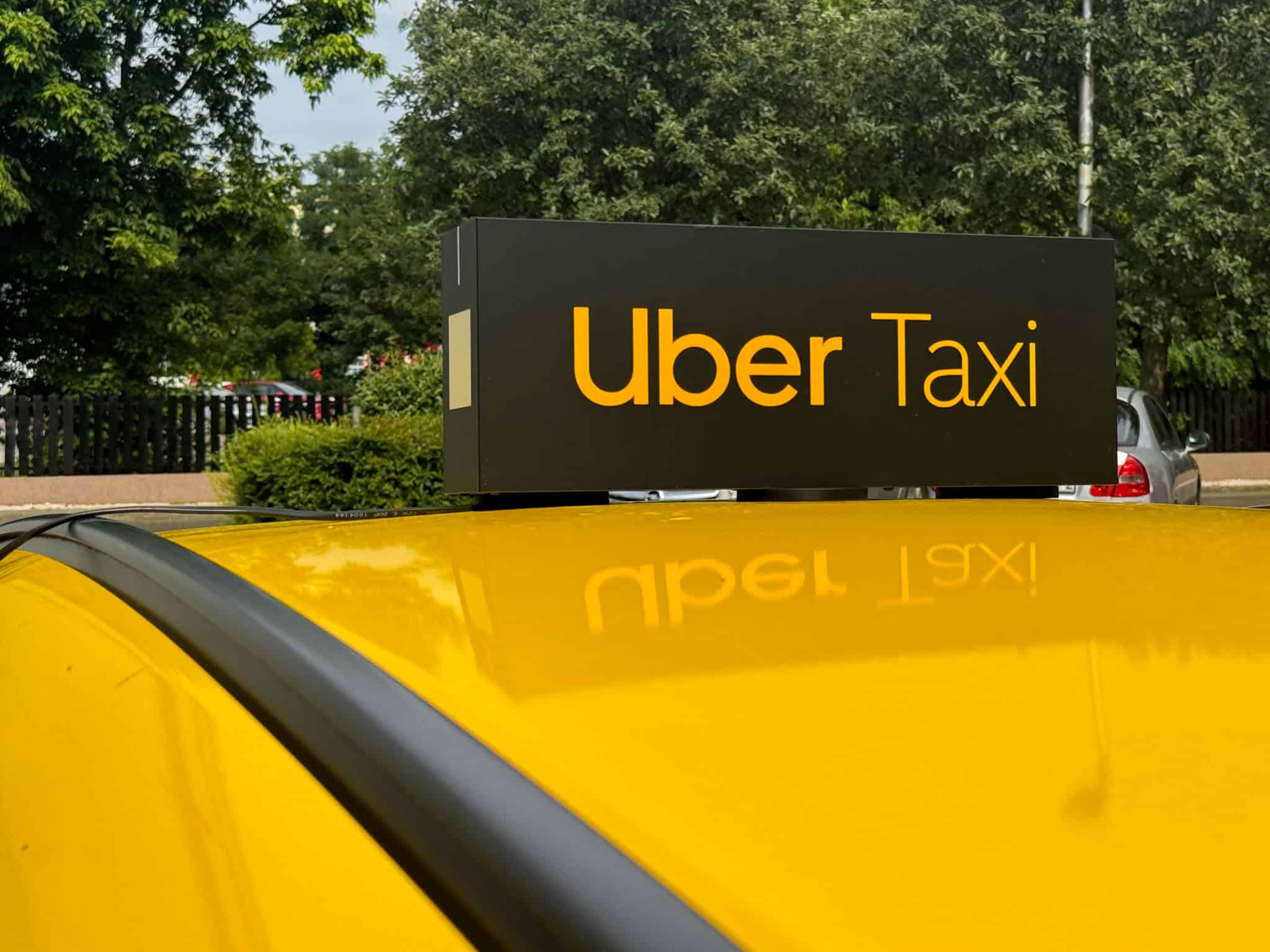 An illuminated Uber Taxi roof sign on a yellow car in Budapest