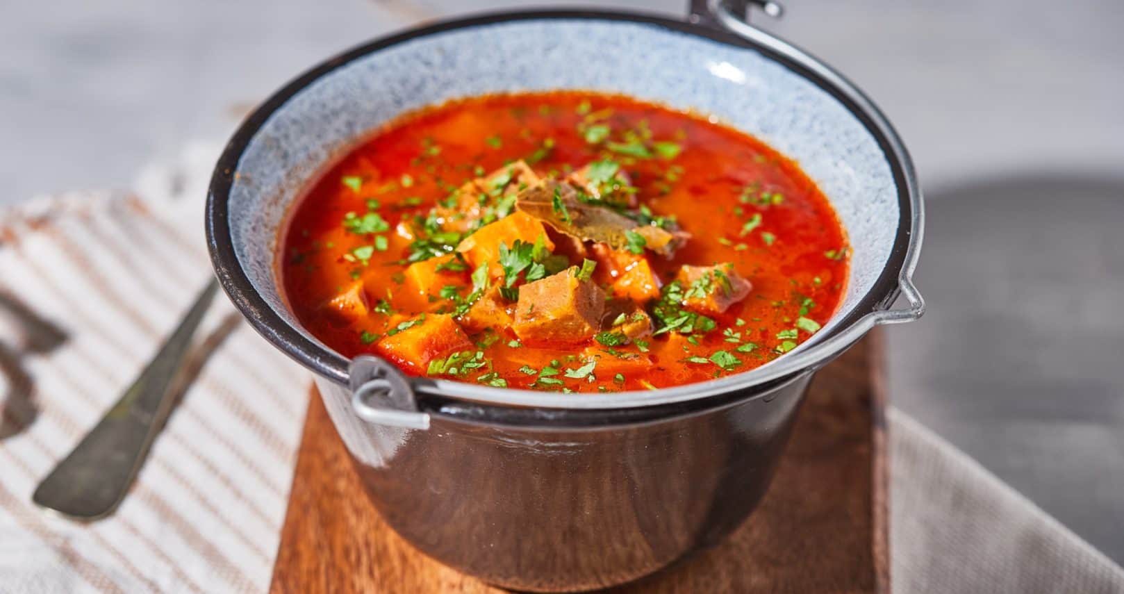 A bowl of rich, red Vegan Hungarian Goulash soup with vegetables