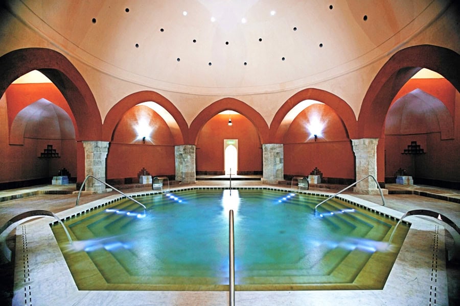 The authentic octagonal thermal pool of the Veli Bej Bath, a historic Turkish bath with red walls and a dome.