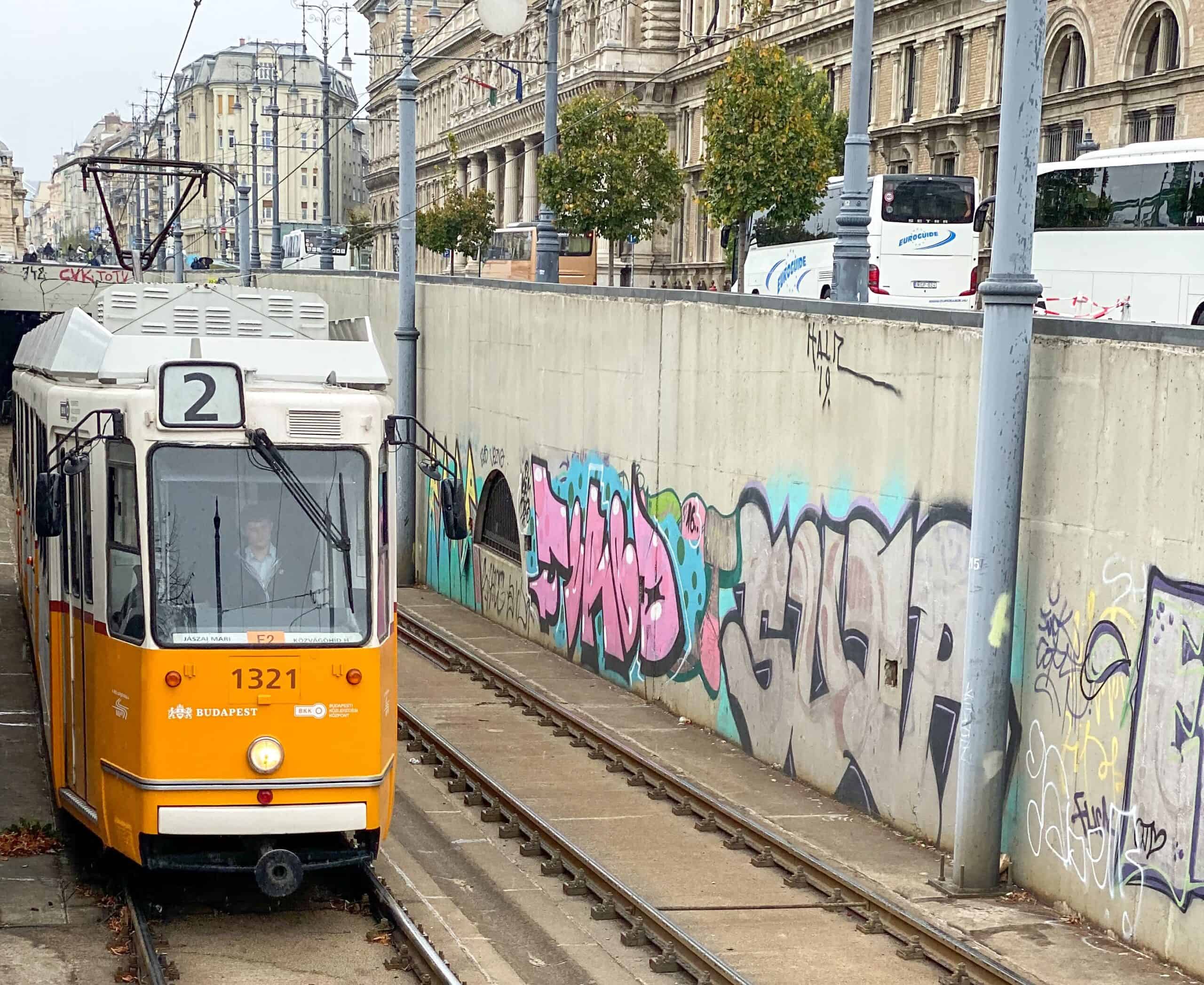 A vintage yellow tram moving through the historic streets of Budapest