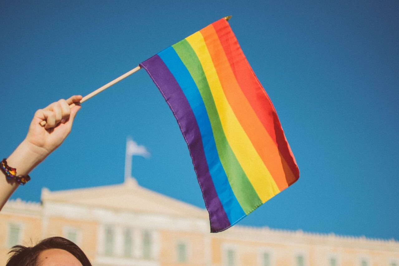 A participant waving a rainbow flag proudly into the blue sky during the festival