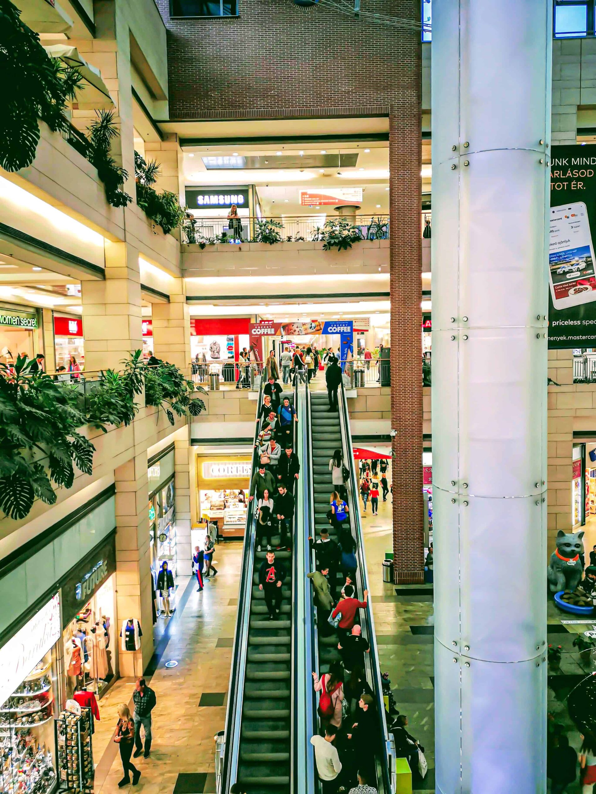 Shoppers walking past modern retail storefronts inside the Westend Mall