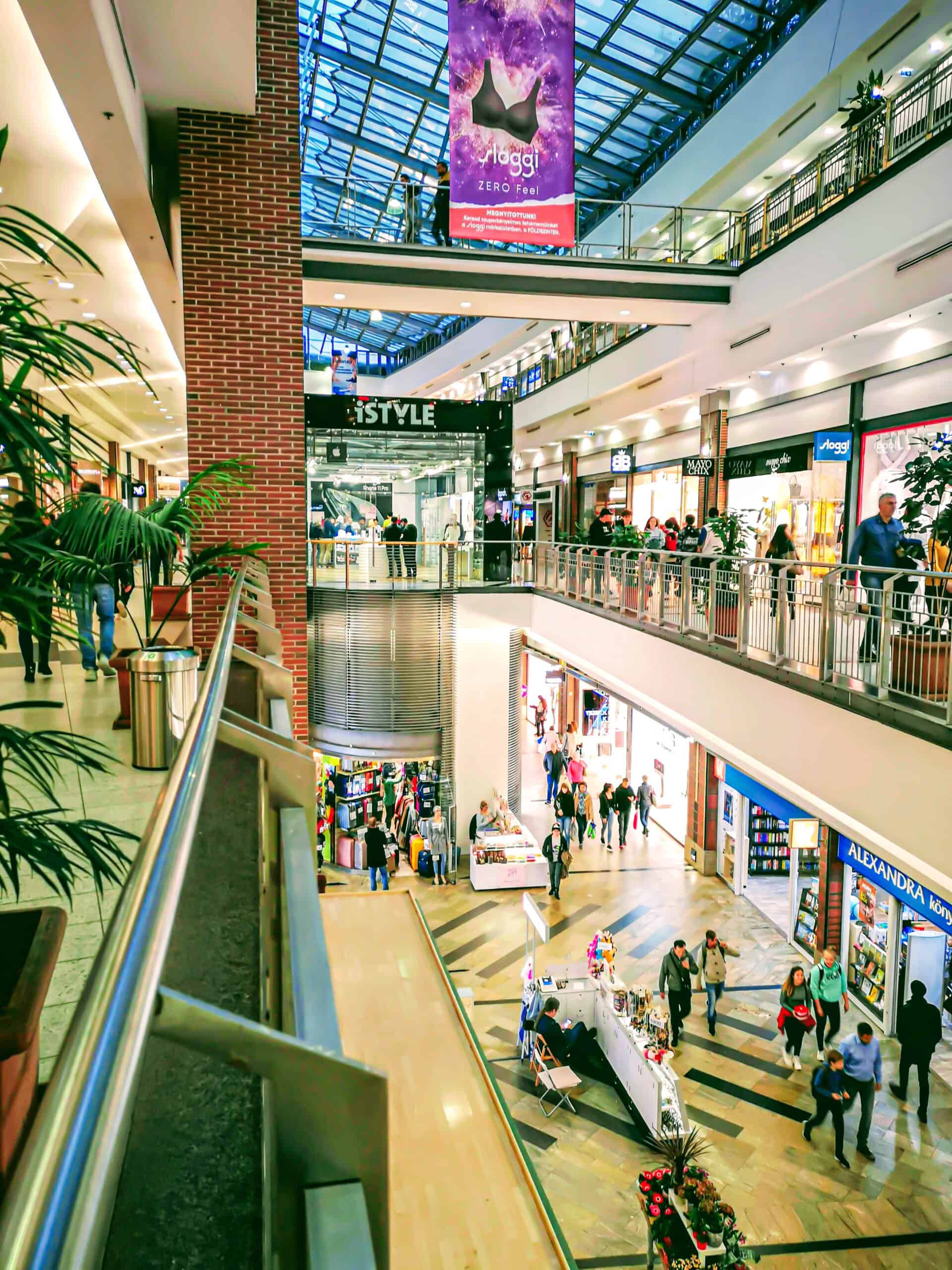 Wide interior view of the glass-roofed Westend shopping mall in Budapest with multiple floors.