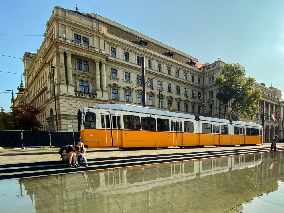 A yellow tram gliding past the Parliament, highlighting safe public transportation